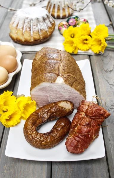 Smoked ham on squared napkin, on wooden table. — Stock Photo, Image