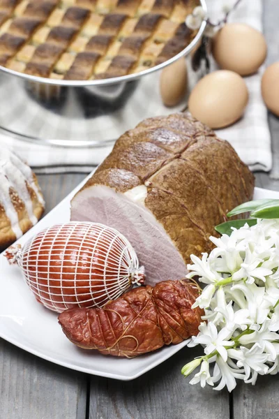 Smoked ham on squared napkin, on wooden table. — Stock Photo, Image