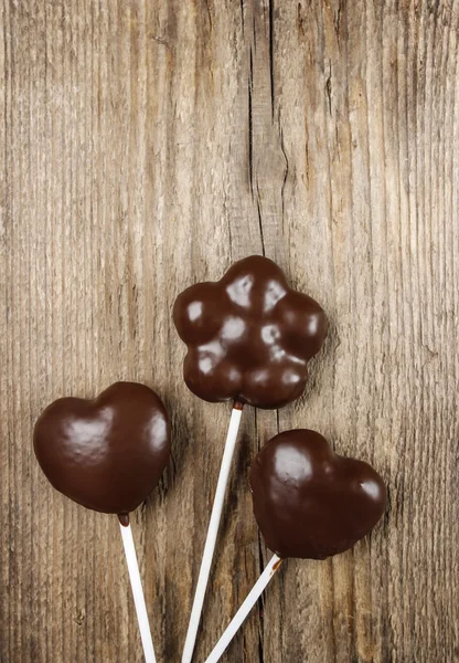 Schokoladenkuchen knallen in Blüten- und Herzformen auf hölzernem Backgro — Stockfoto