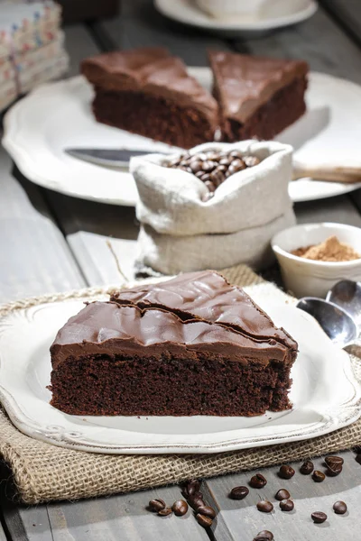 Pastel de chocolate en plato blanco, en hessian. Granos de café en woode — Foto de Stock