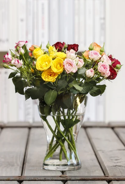 Strauß bunter Rosen in Glasvase auf einem Holztisch — Stockfoto