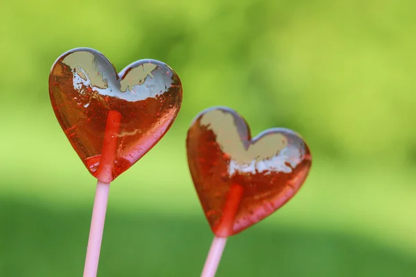 Red lollipops in heart shape, on fresh green grass, in the garde — Stock Photo, Image
