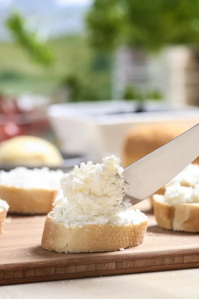 Preparing canapes with fresh cottage on wooden kitchen table — Stock Photo, Image