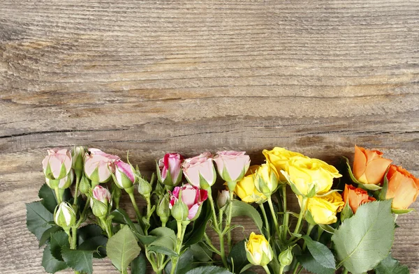 Superfície de madeira com espaço de cópia decorado com rosas coloridas — Fotografia de Stock