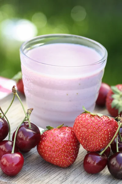Strawberry milkshake på träbord bland färska frukter — Stockfoto