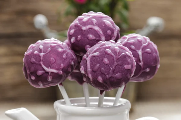 Lila cake pops i vit keramik kruka på trä bakgrund. — Stockfoto