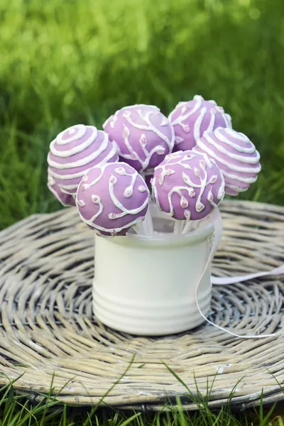 Lilac cake pops in white ceramic jar on wicker tray — Stock Photo, Image