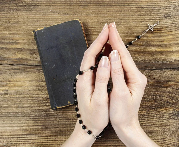 Hands holding the Bible and praying with a rosary — Stockfoto