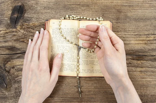 Hands holding the Bible and praying with a rosary — Stock Photo, Image