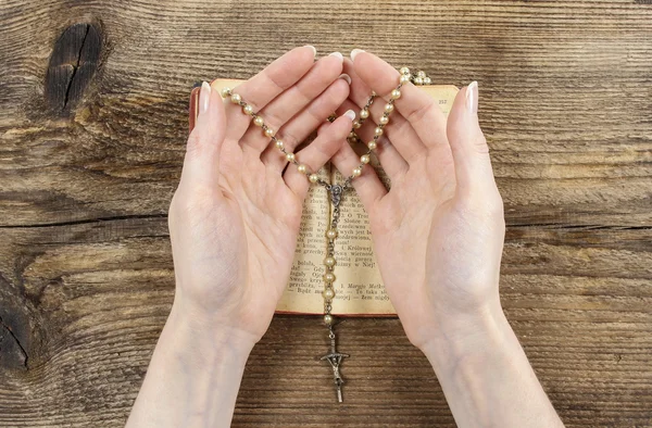 Руки держат Библию и молятся с четками — стоковое фото