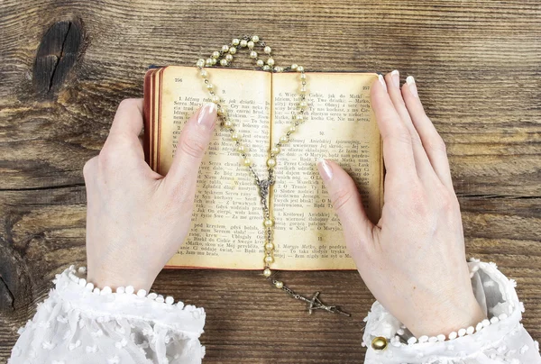 Hands holding the Bible and praying with a rosary — Stockfoto