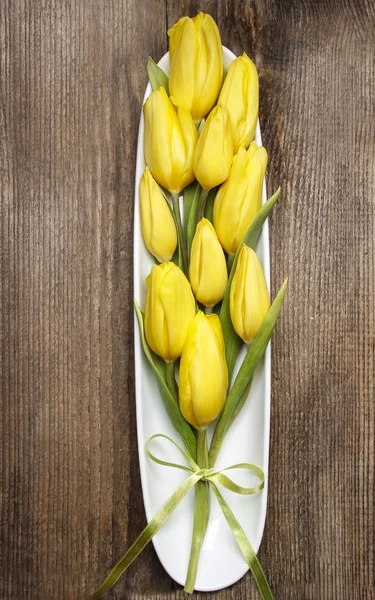 Bouquet de tulipes jaunes sur fond bois brun . — Photo