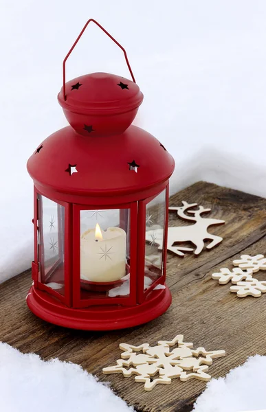 Lanterna vermelha em pé sobre placa de madeira, na neve — Fotografia de Stock