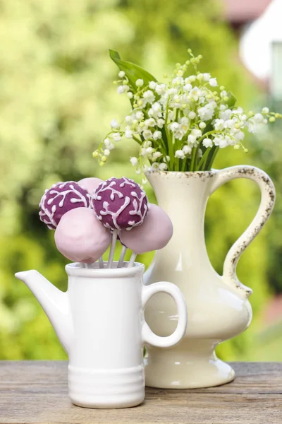 Lilly dalen blommor och pastell cake pops på träbord — Stockfoto