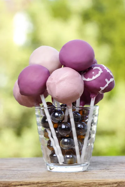 Violet and lilac cake pops on wooden rustic table in summer gard — Stock Photo, Image