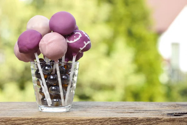 Violet and lilac cake pops on wooden rustic table in summer gard — Stock Photo, Image