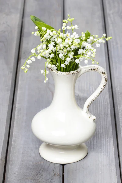Lilly, a völgy virágok fehér rusztikus vázában a szürke fa — Stock Fotó