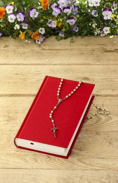 New red Holy Bible and white rosary on old wooden surface. — Stock Photo, Image