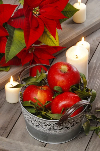 Silver bucket of red ripe apples among candles — Stock Photo, Image
