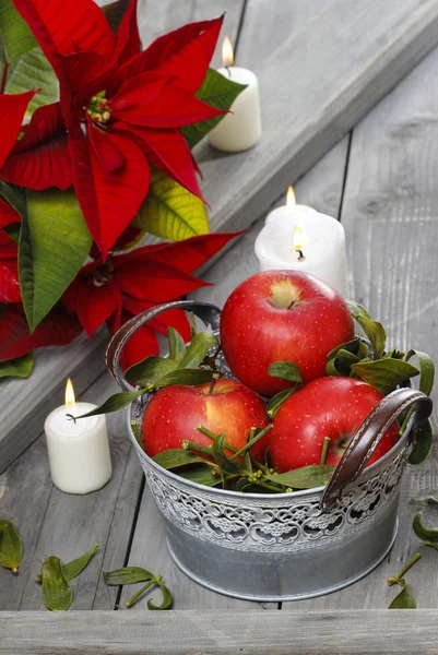 Silver bucket of red ripe apples among candles — Stock Photo, Image