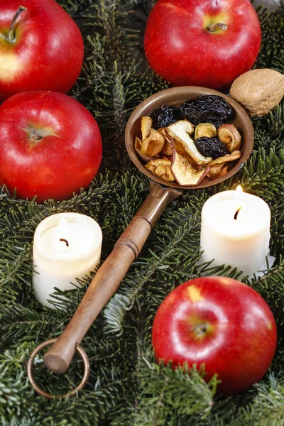 Frutos secos em ramos de abeto entre maçãs maduras vermelhas e velas . — Fotografia de Stock