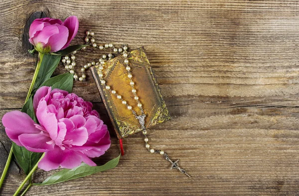 Pink peony, vintage book and white rosary on wooden background. — Stock Photo, Image