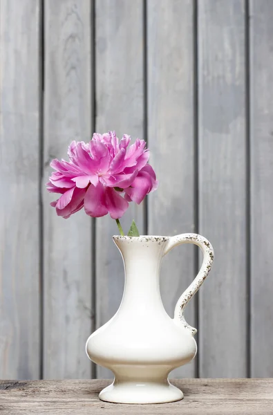 Egyetlen rózsaszín bazsarózsa fa rusztikus háttéren fehér vázában — Stock Fotó