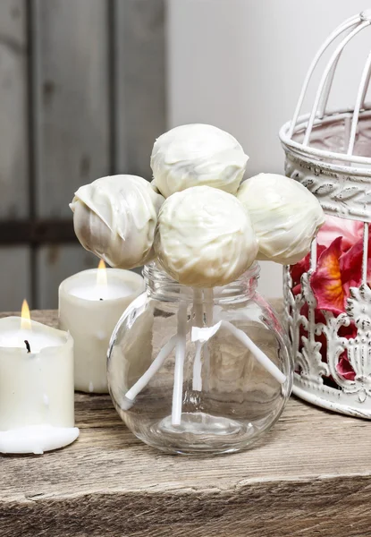 White chocolate cake pops in glass jug on wooden table. — Stock Photo, Image