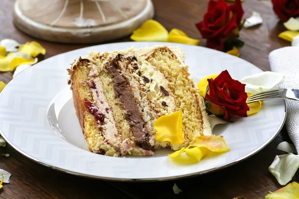 Piece of wedding cake among rose petals — Stock Photo, Image