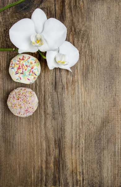 Bovenaanzicht van orchideeën en muffins op houten tafel — Stockfoto