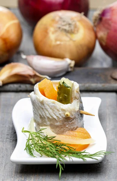 Pickled herring rolls with vegetables on wooden table — Stock Photo, Image