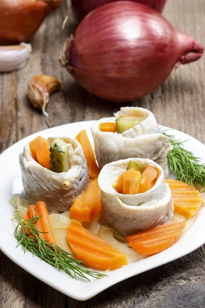Pickled herring rolls with vegetables on wooden table — Stock Photo, Image