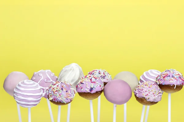 Pink cake pops on yellow background. Copy space
