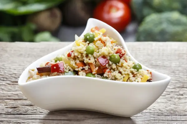 Couscous with fresh vegetables on wooden table. — Stock Photo, Image