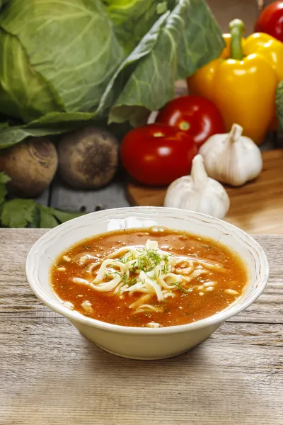 Bowl of tomato soup and fresh vegetables on old wooden table — Stock Photo, Image