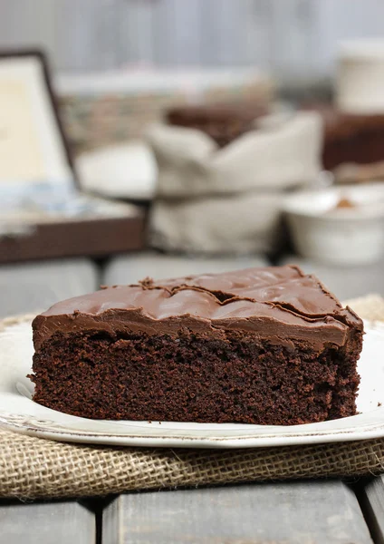 Pastel de chocolate en plato blanco, en hessian. Granos de café en woode — Foto de Stock