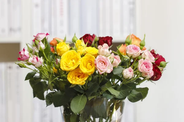 Strauß bunter Rosen in Glasvase auf einem Holztisch — Stockfoto