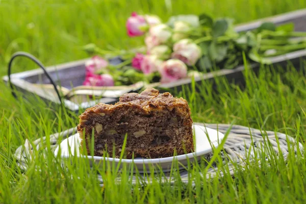 Przyjęcie w ogrodzie. tort czekoladowy na tacy wikliny, na zielony świeży gras — Zdjęcie stockowe