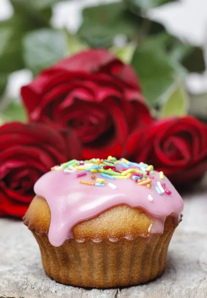 Muffins cobertos com cobertura rosa e polvilhas coloridas em madeira — Fotografia de Stock