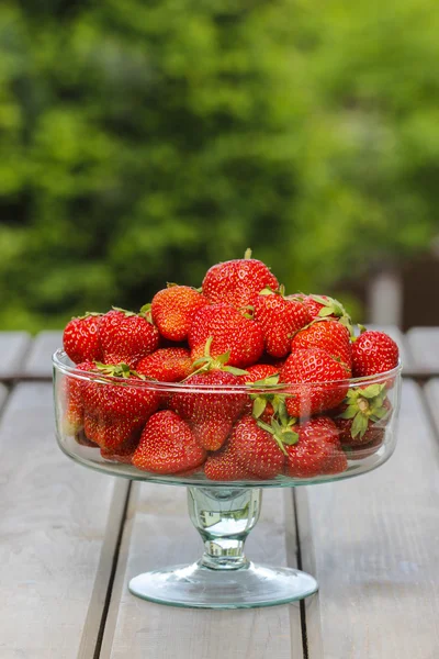 Cuenco de vidrio de fresas frescas maduras en mesa de madera rústica en — Foto de Stock