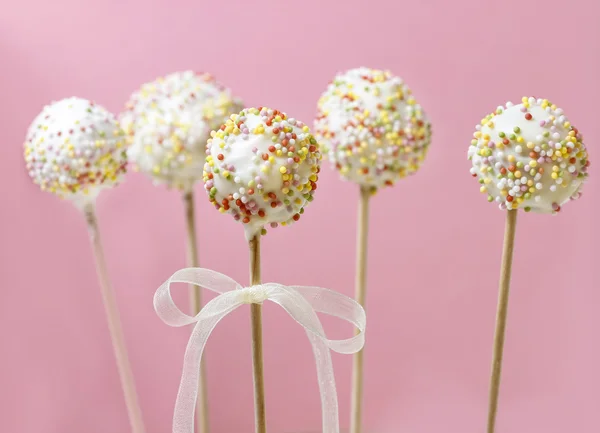 Pop koláče zdobené postřikovačů na růžovém pozadí — Stock fotografie