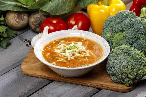 Zupa pomidorowa i świeże, surowe warzywa w tle. — Zdjęcie stockowe