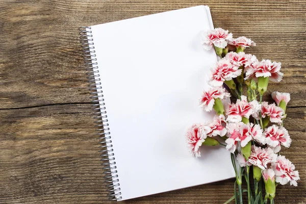 Vista superior de hoja en blanco de cuaderno y clavel rojo y blanco — Foto de Stock