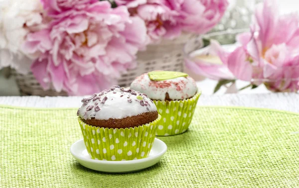 Cupcakes auf grüner Serviette. atemberaubende Pfingstrosenblüten im Hintergrund — Stockfoto