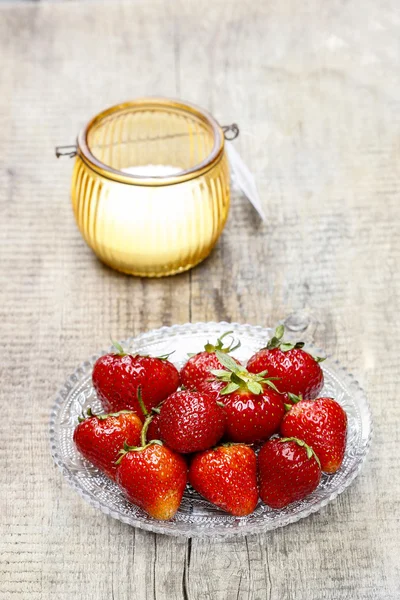 Aardbeien en één oranje kaars op rustieke houten tafel — Stockfoto