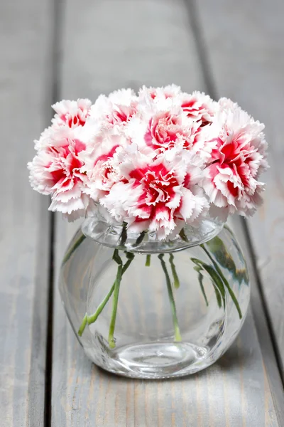 Bouquet of carnation flowers in glass vase on wooden table — Stock Photo, Image