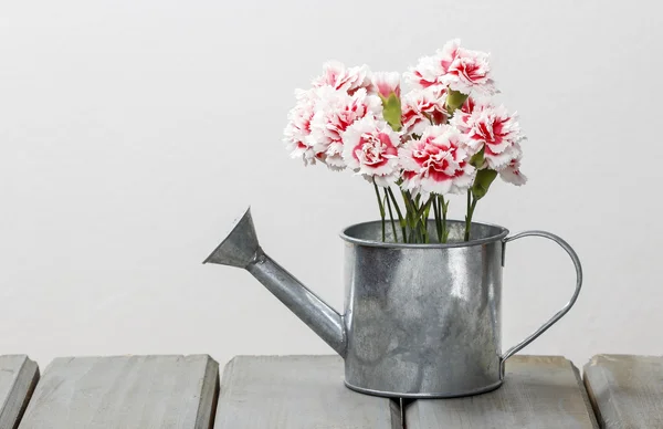 Beautiful pink carnation flowers in silver watering can, on wood — Stock Photo, Image