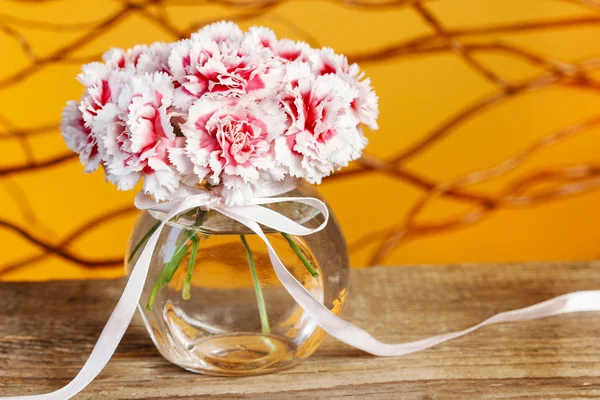 Boeket van carnation bloemen in glazen vaas op houten tafel — Stockfoto