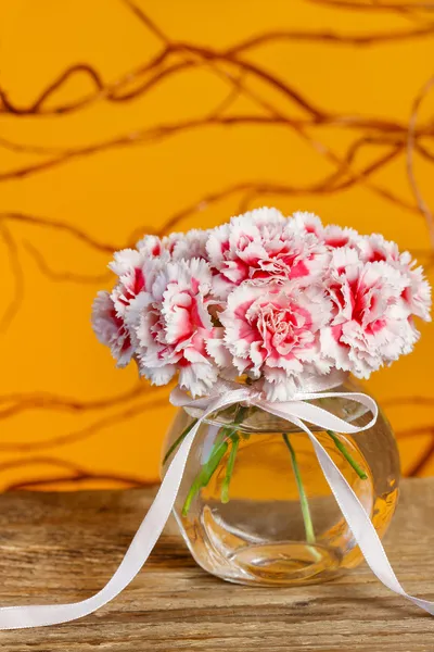 Bouquet of carnation flowers in glass vase on wooden table — Stock Photo, Image