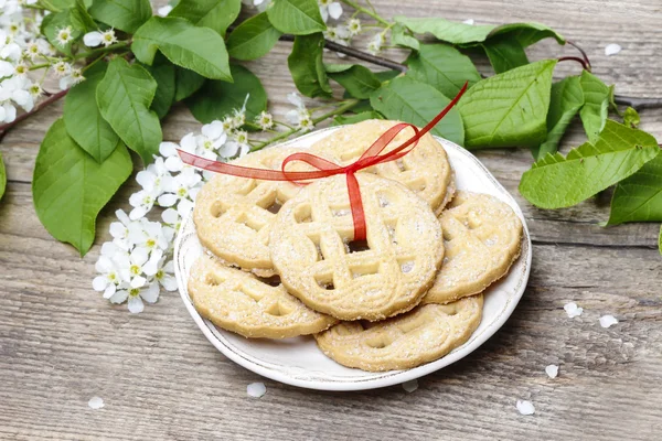 Round biscuits with red bow in spring setting. Wooden table — Stock Photo, Image